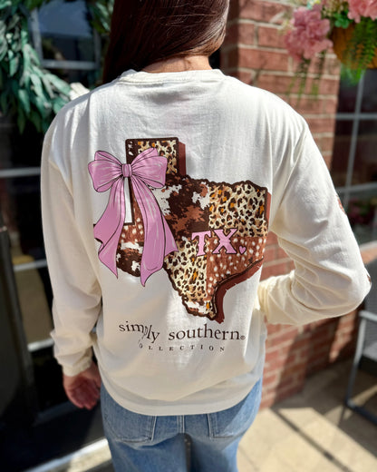 Cream Texas Animal Print Long Sleeve featuring a graphic of Texas in cow leopard print with a pink bow and “TX” on the back, plus “simply southern collection” below. Available in sizes S–XXL.