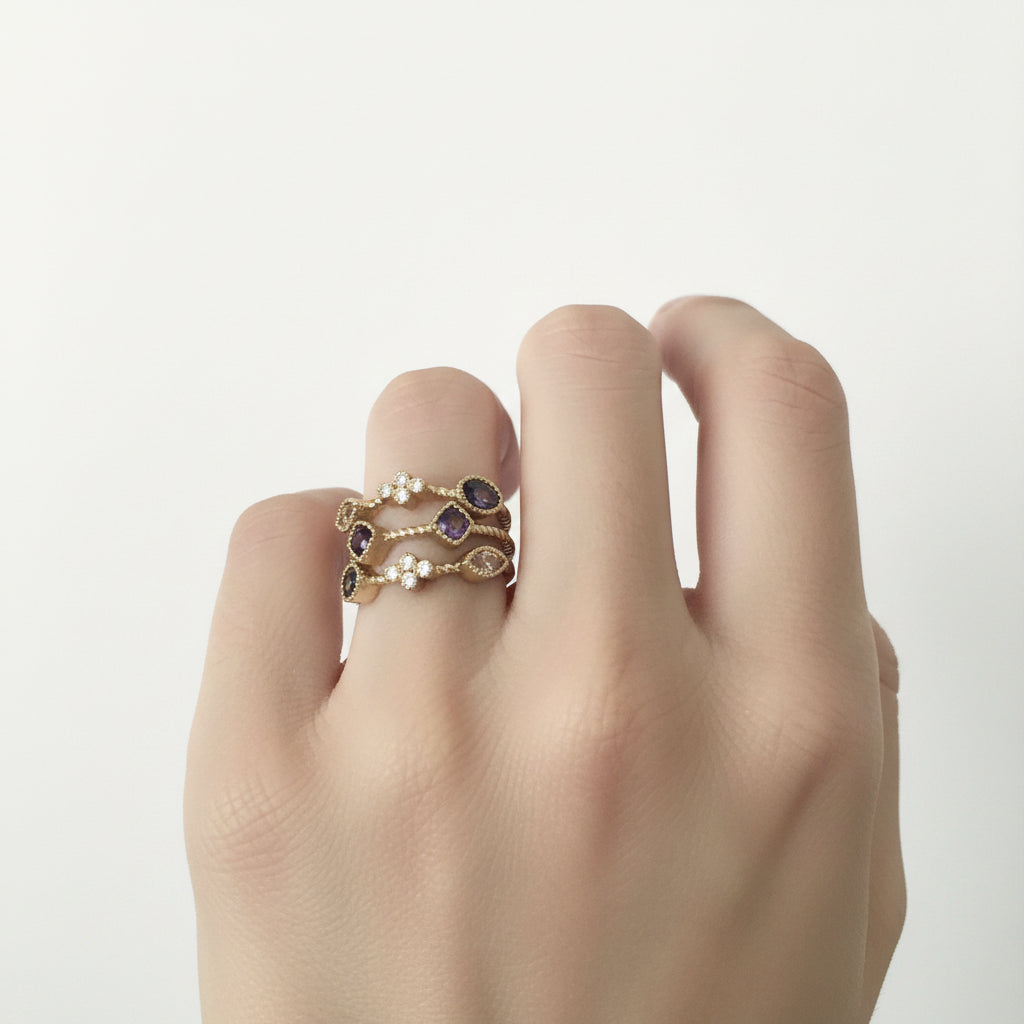 Two stackable gold rings with small purple gemstones and white pearls. Available in sizes 5-9.