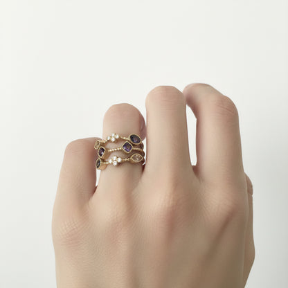 Two stackable gold rings with small purple gemstones and white pearls. Available in sizes 5-9.