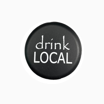 Round black wine stopper with "drink LOCAL" in white text. Available in multiple sizes.