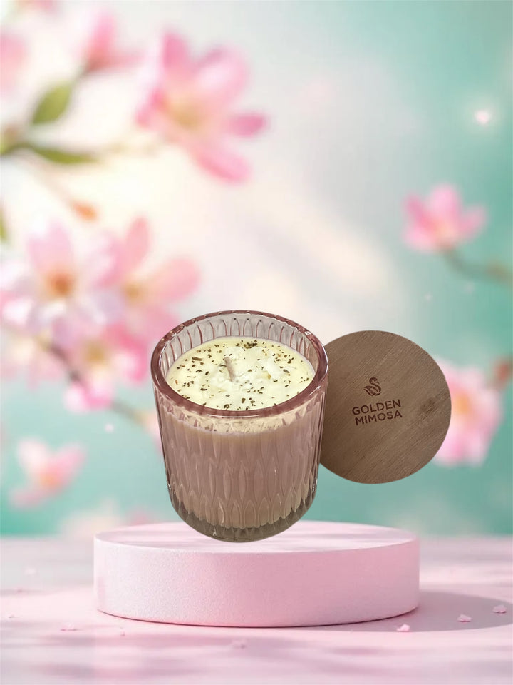Golden Mimosa Cathedral Candle in a pink glass jar with a textured base and a wooden lid.
