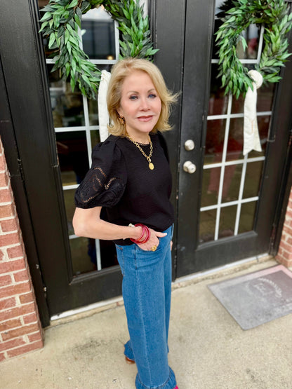 Haley Black Top with embroidered eyelet sleeves, available in sizes XS–XL.