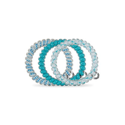 Three TELETIES Hair Ties: two clear with blue stripes, one solid turquoise, each with a small charm. Available in various sizes.