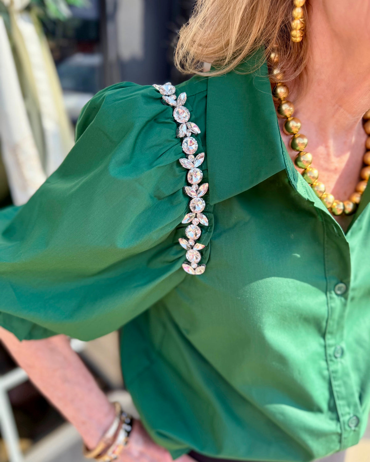 Hadley Blouse in hunter green with sparkling rhinestone shoulder embellishments; available in sizes XS–XL.