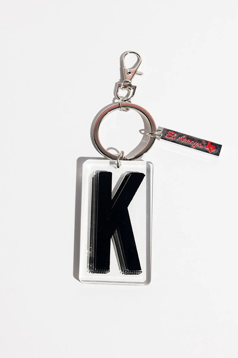 Black "K" keychain in clear acrylic, silver keyring, red text tag. Available in one size.