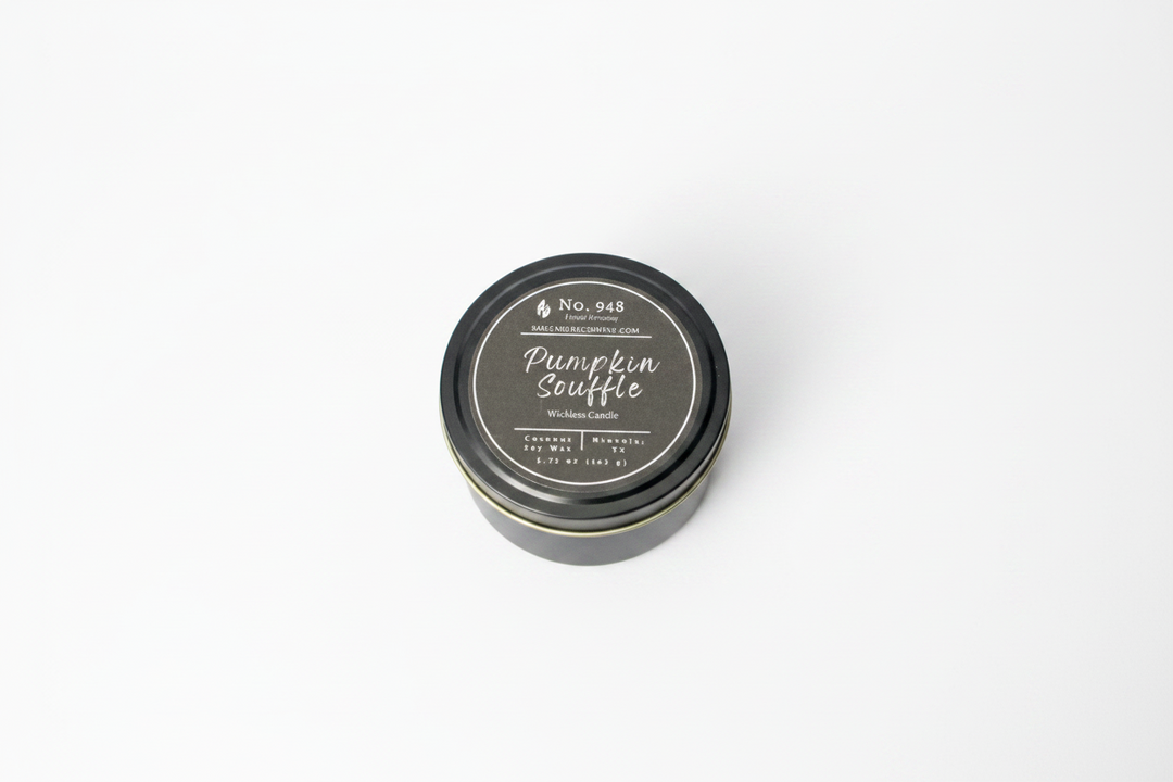 A small, round black tin labeled "Wickless Candle 5.75 oz" in coconut soy wax with "Pumpkin Souffle" and product details on the lid; available in 5.75 oz size.