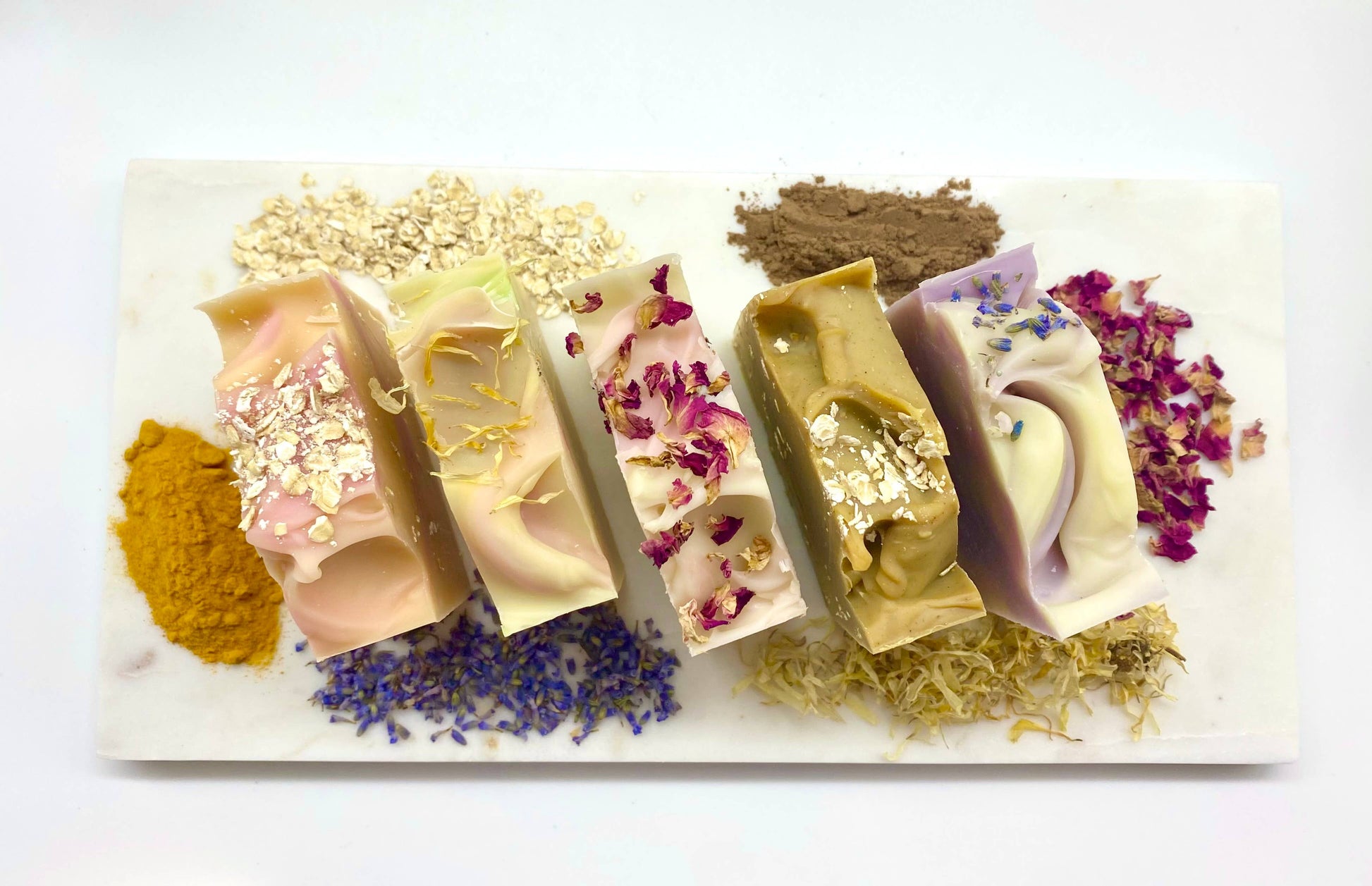 Handmade Bamboo Bergamot Soap Bars artfully crafted with natural ingredients such as oatmeal, lavender, and rose petals. Each bar boasts unique colors and patterns. Encased on an elegant marble slab. Available in various sizes.