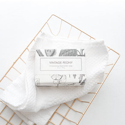 The product is a "Vintage Peony Soap - Bath Bar". It's wrapped in elegant packaging and delivers a luxurious bathing experience. It features a soft, floral fragrance that adds charm to your daily routine. Comes as a single bar.