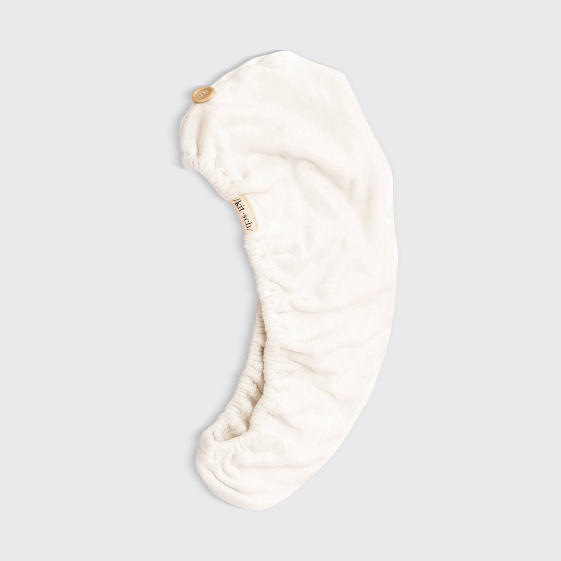 Cream-colored microfiber hair towel wrap with button closure; eco-friendly. Available in S/M and L/XL. Quick-drying care.