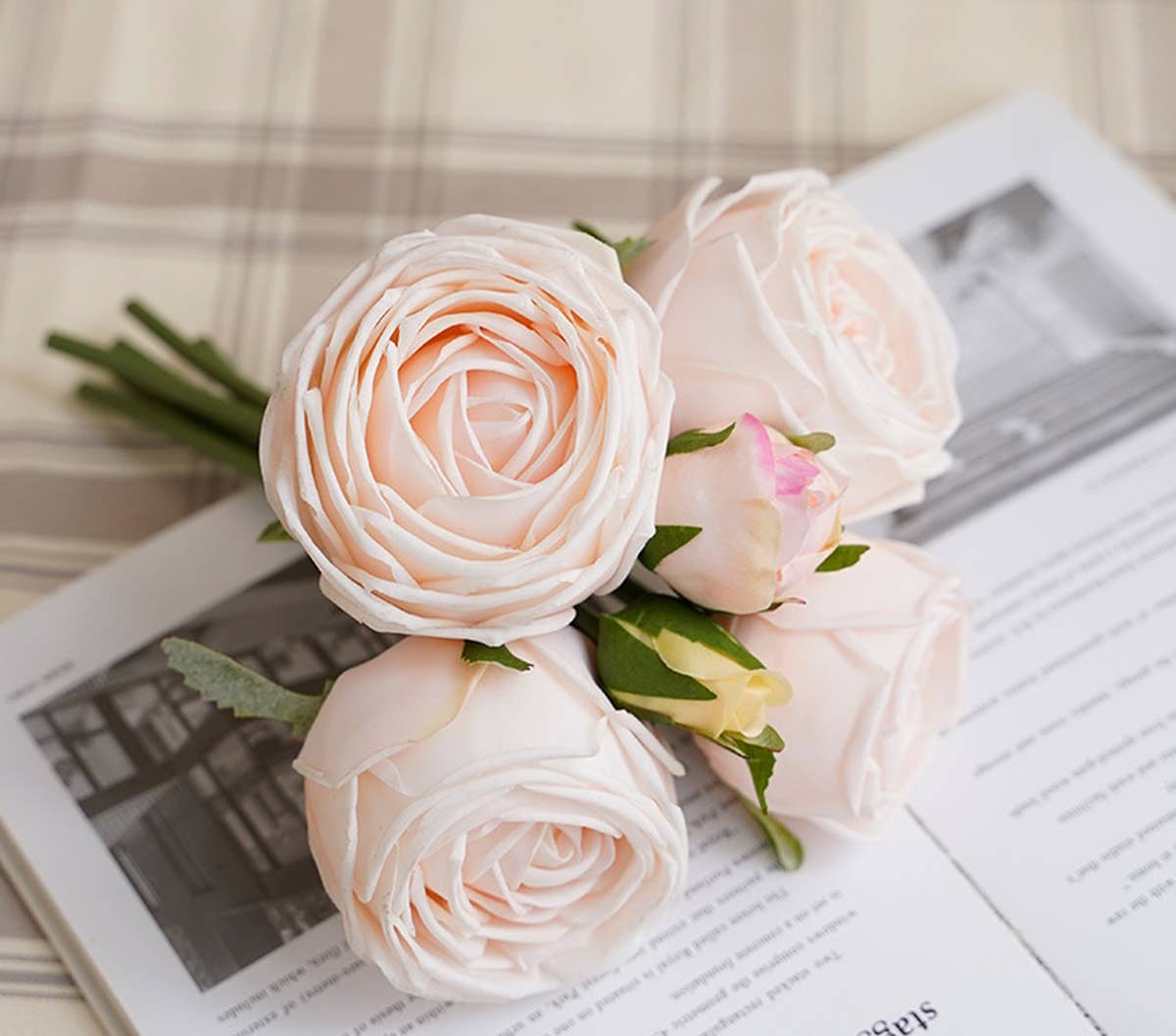 A 6-stem bouquet of Real Touch roses, fully bloomed with smaller buds; available on open text-lined book with a plaid fabric backdrop. Sizes: One size available.