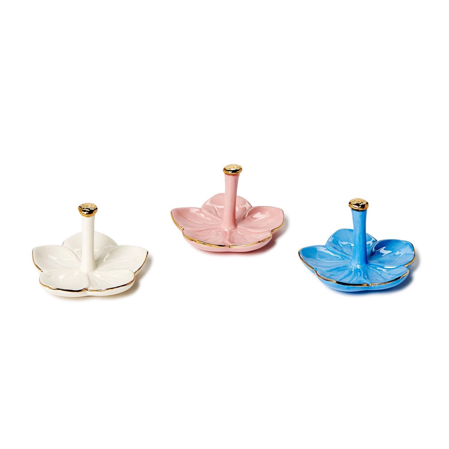 Set of three flower-shaped ceramic ring holders in white, pink, and blue with gold-tipped stems. Sizes: small, medium, large.