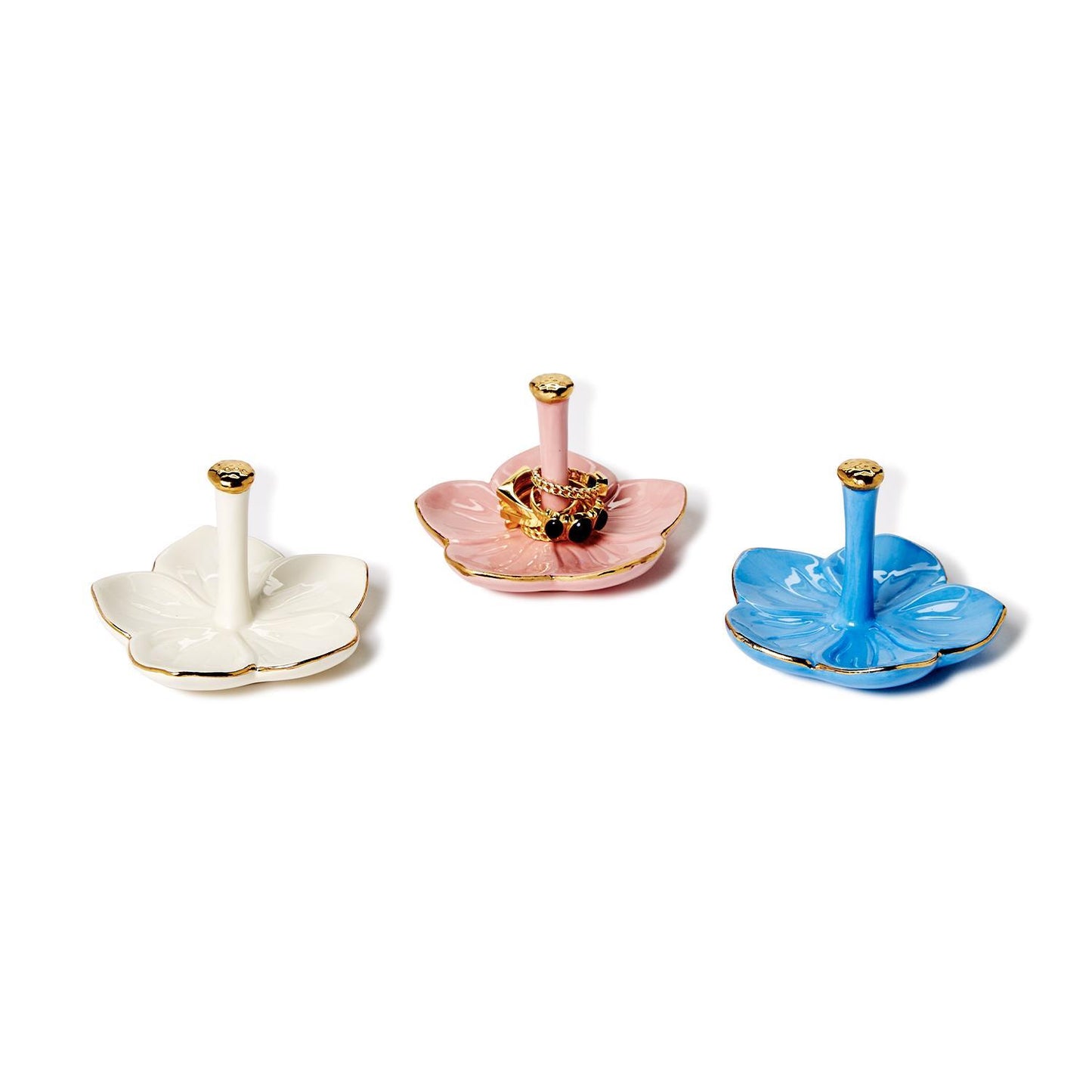 Three ceramic flower-shaped ring holders in white, pink (bee detail), and blue with gold. Sizes: small, medium, large.