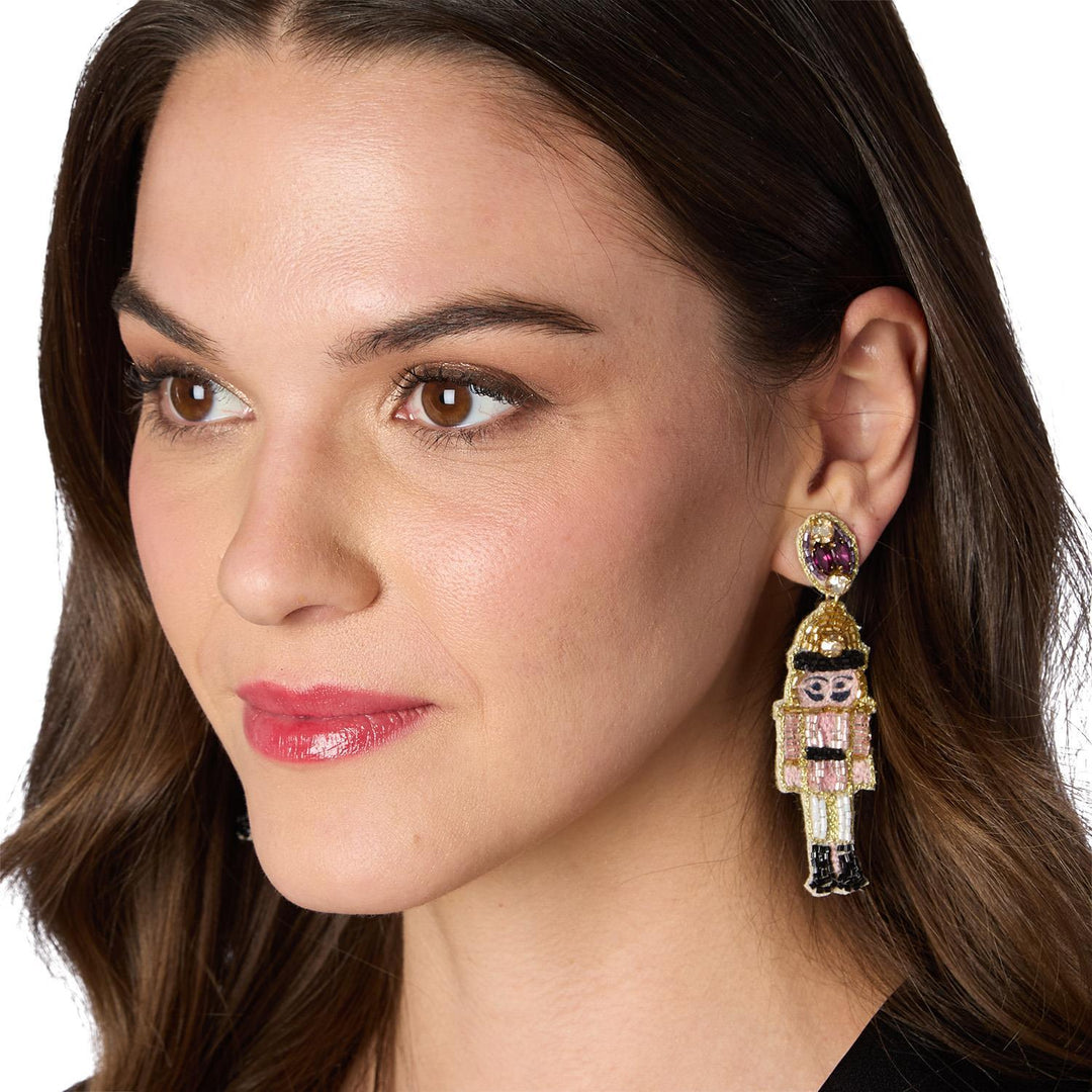 Holiday Icon Earrings: beaded nutcracker charm with a round purple gem.