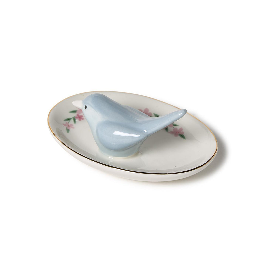 Small oval ceramic ring holder with blue bird figurine, floral design, gold rim. Available in one size.