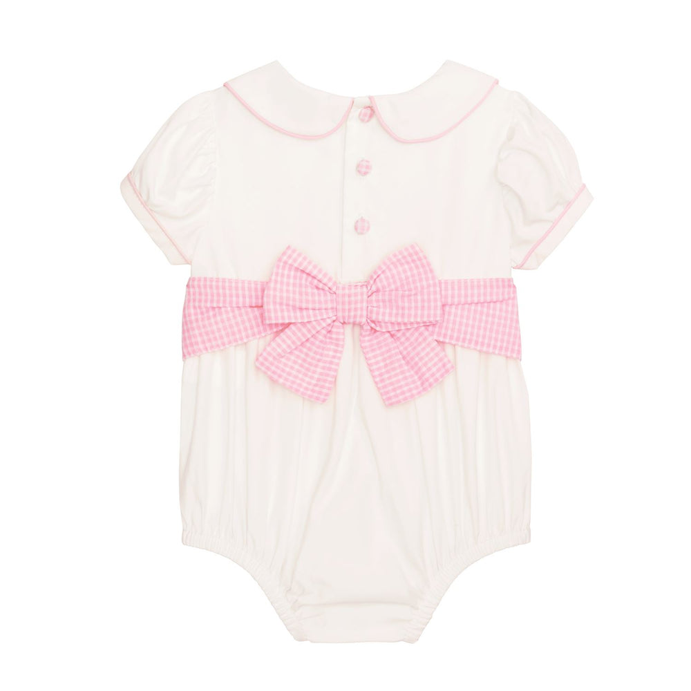 White baby romper with pink trim, large gingham bow, Peter Pan collar, pink back buttons. Sizes: NB-24M.