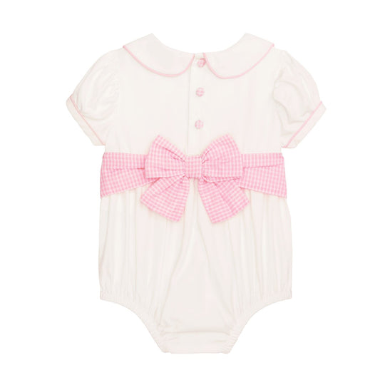 White baby romper with pink trim, large gingham bow, Peter Pan collar, pink back buttons. Sizes: NB-24M.