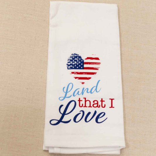 White cotton hand towel with heart-shaped American flag and "Land that I Love" in blue/red. Easy care. Size: not specified.