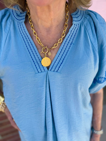 Light Blue Embroidered Puff Sleeve Top with dark blue stitching, available in sizes XS-XL.