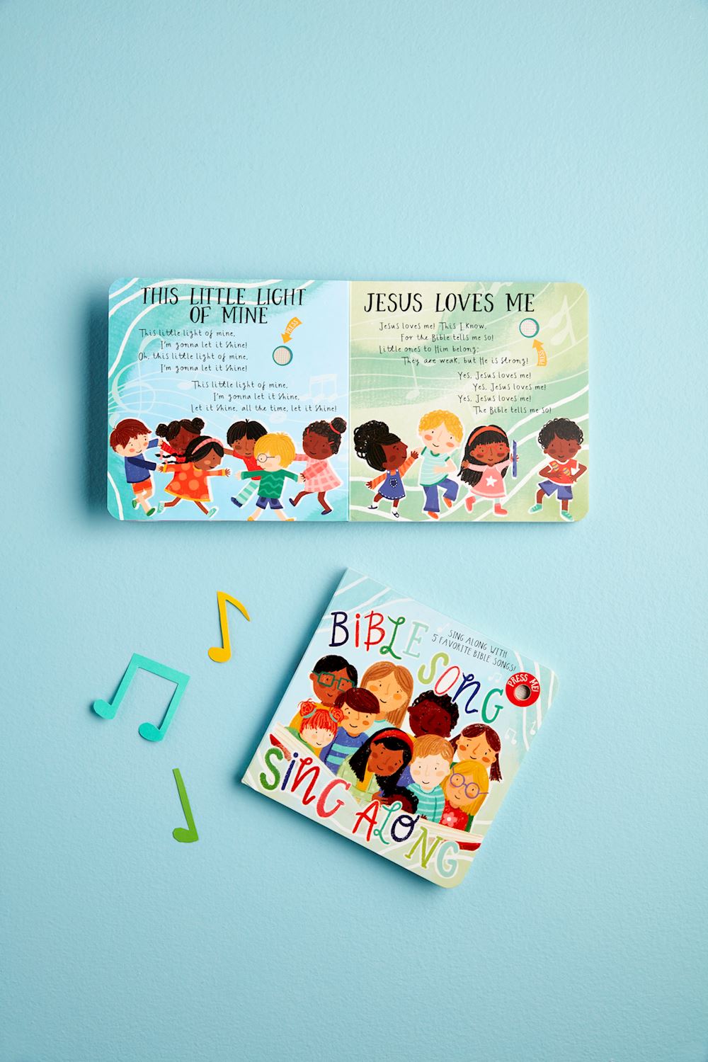 The "Bible Song Book" is a sing-along book featuring children singing popular Sunday School songs. It includes lyrics for "This Little Light of Mine" and "Jesus Loves Me," accompanied by colorful musical notes. Sizes available: Not specified.