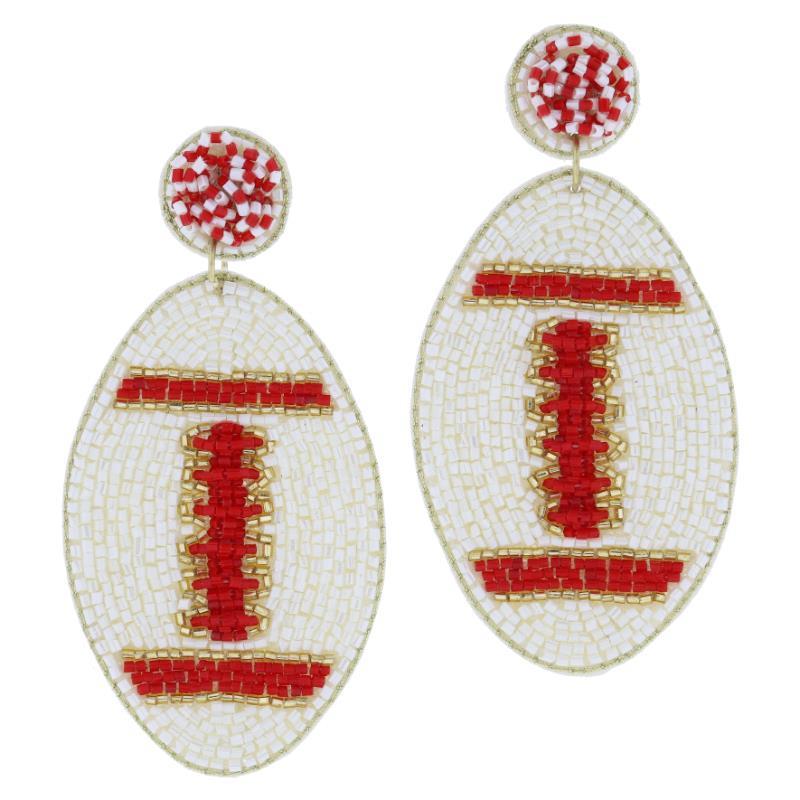 Ideal for game day accessories, the Beaded Post with Gold Beaded Football Earrings showcase small white beads forming an oval shape, with red and white beads intricately crafting the laces and detailing. Each earring dangles from a circular post. Available in one size.