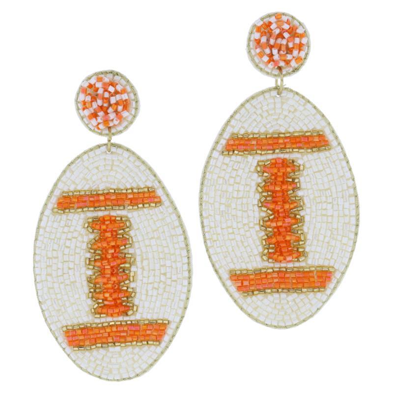 The Beaded Post with Gold Beaded Football Earrings feature intricate designs with white, orange, and gold beads. Circular tops, oval bottoms, horizontal patterns on a white beaded background. Available in one size.