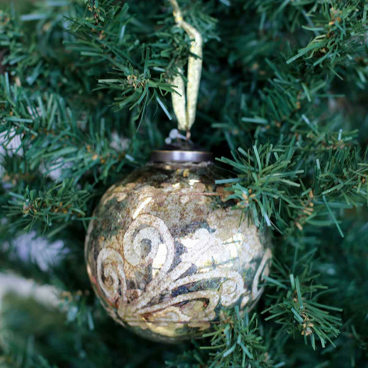 Distressed gold glass ornament ball with embossed scrollwork.