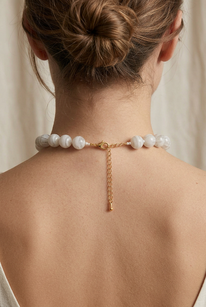 Marbled beaded necklace with round white-and-grey beads, gold-tone clasp, and extender chain. Available in all sizes.