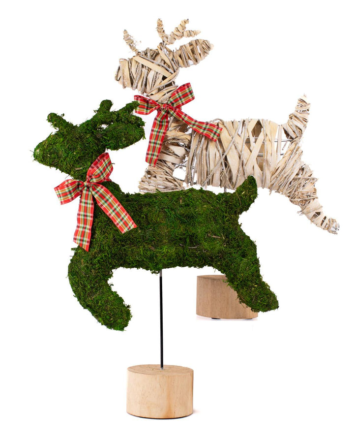 Two Vixen Leaping Deer holiday figurines on wooden bases: one moss-covered, one woven wood, both with plaid bows.