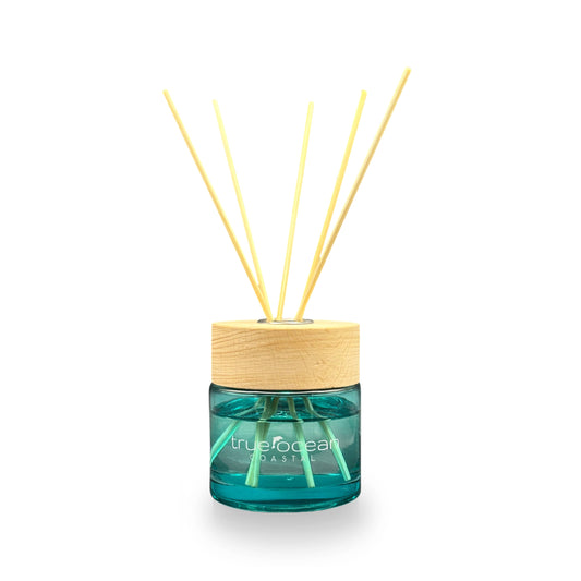 Blue glass jar with wooden lid and light reed sticks. The True Ocean: Reed Diffuser. Available in 100ml and 200ml sizes.