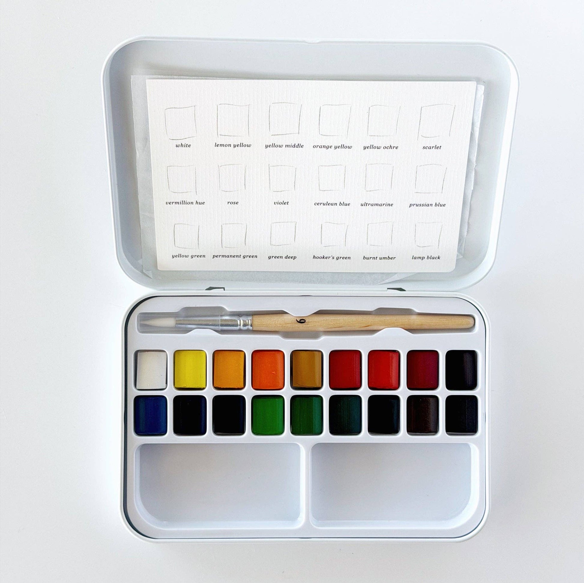 Compact watercolor set with 18 pans, a wooden-handled brush, paint swatch card, all in a white tin box. Available in travel size.