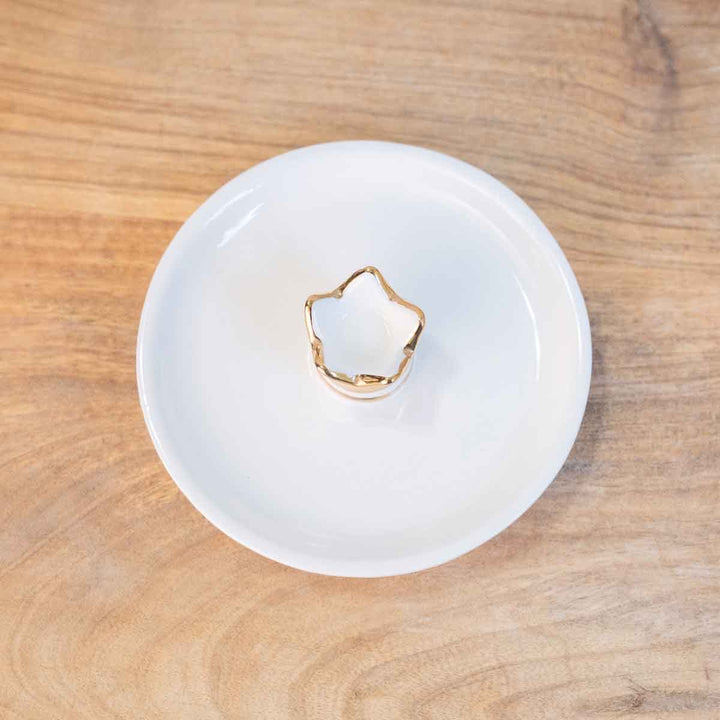 The Her Highness Trinket Dish is a star-shaped candle with a gold rim, set on a round white plate. Available in one size: 4"x4" dish.