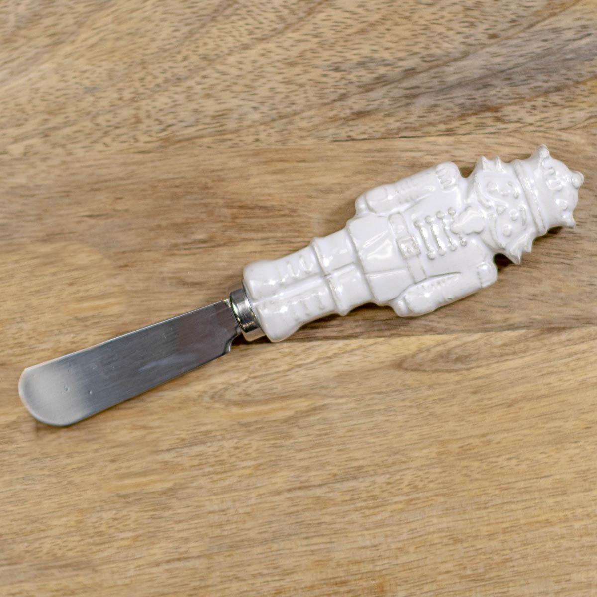 **The Royal Nutcracker Spreader:** A festive spreader with a white ceramic handle shaped like a nutcracker soldier. Available in standard size.