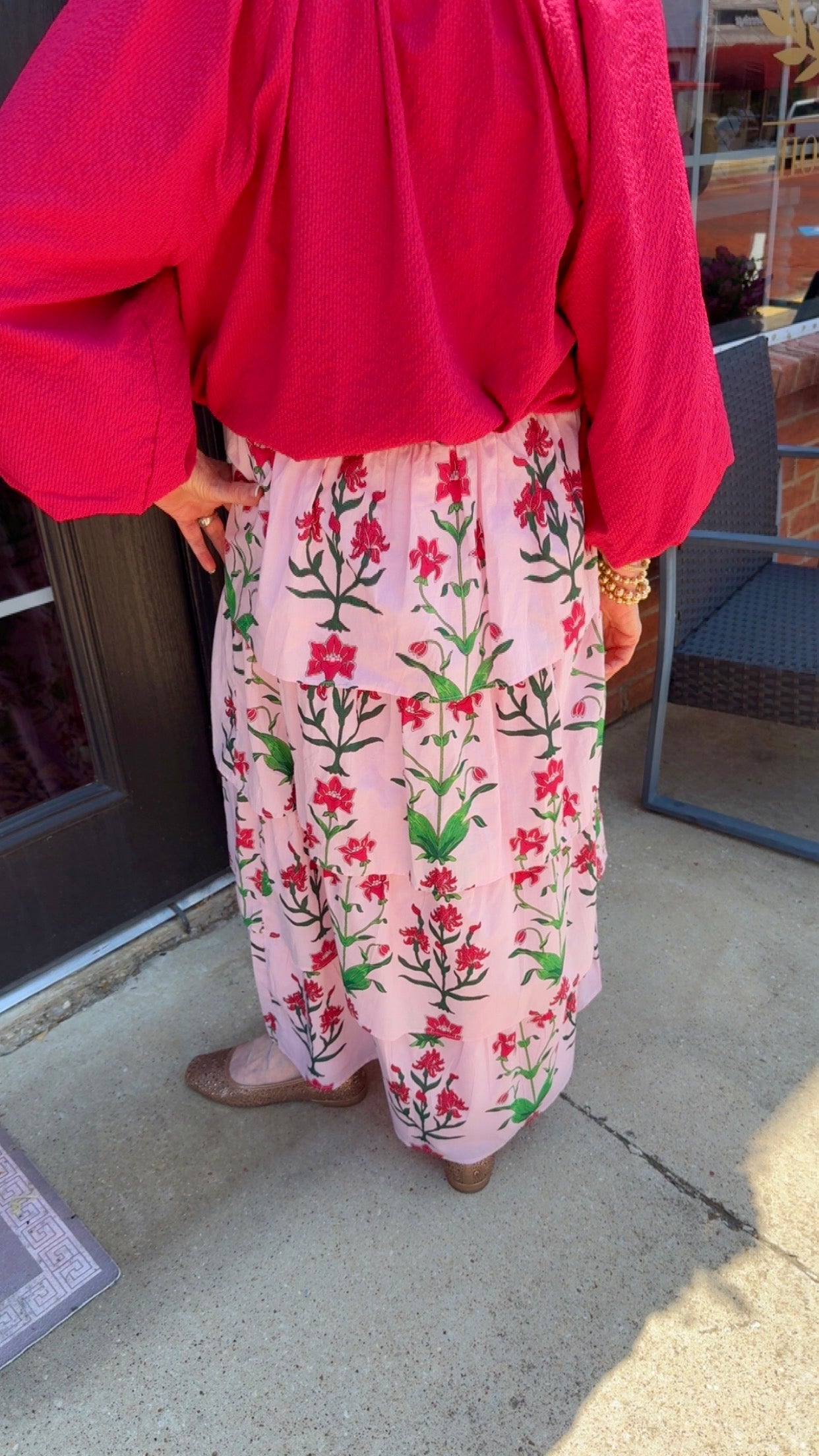 Rose d’Iris Ruffle Cascade Maxi Skirt in light pink with red and green floral pattern, available in sizes XS–XL.