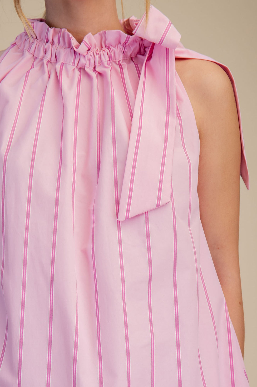 Pinstripe Pink Tie-Neck Sleeveless Dress with ruffled neckline, one-shoulder bow. Available in sizes XS-XL.