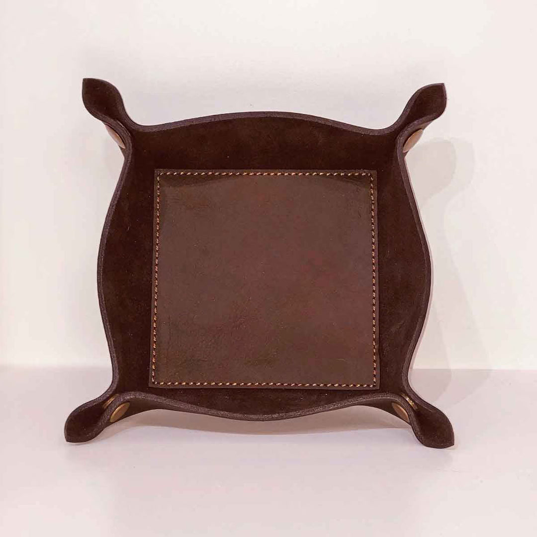 The Leather Embossed Valet Tray is a dark leather accessory with rounded, upturned corners and visible stitching. Available sizes: Small, Medium, Large.