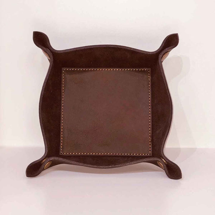 The Leather Embossed Valet Tray is a dark leather accessory with rounded, upturned corners and visible stitching. Available sizes: Small, Medium, Large.