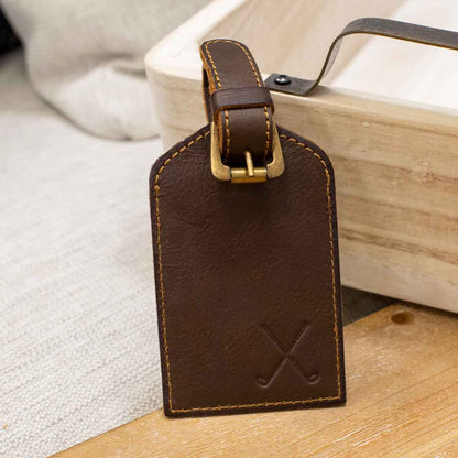 The Leather Embossed Luggage Tag features stitched edges, a gold buckle, and an embossed "X." Available sizes: One Size.