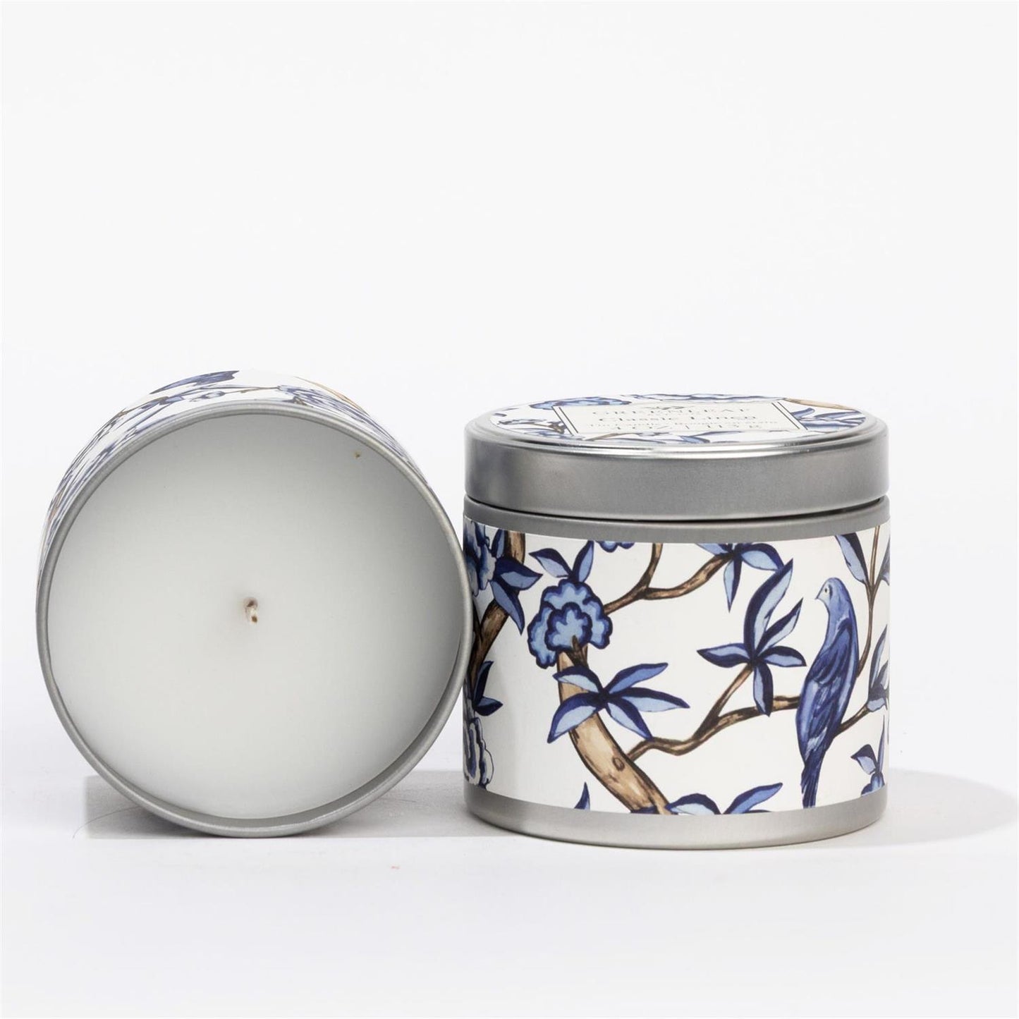 Classic Linen Tin Candle: white tin, blue and white floral and bird design, fresh Greenleaf scent. Available in multiple sizes.