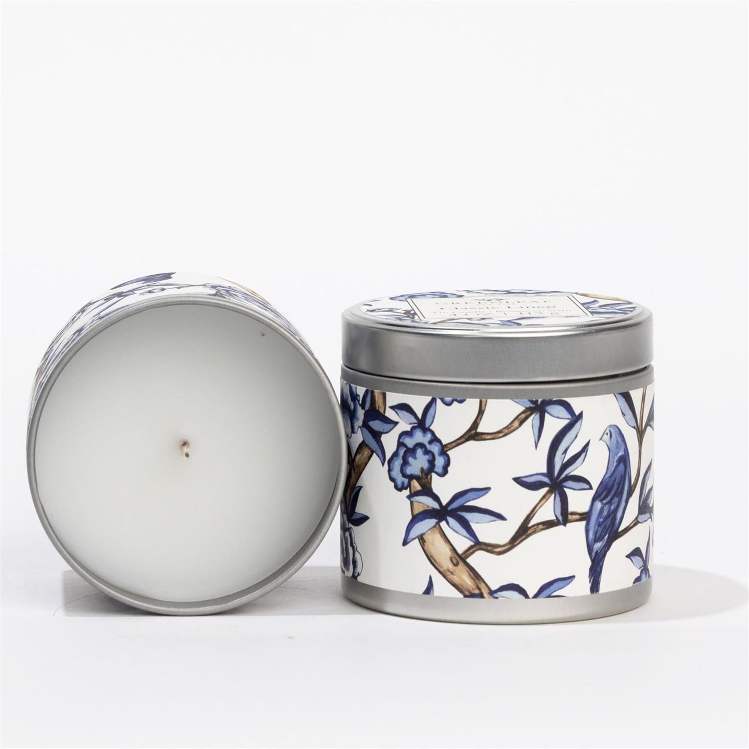Classic Linen Tin Candle: white tin, blue and white floral and bird design, fresh Greenleaf scent. Available in multiple sizes.