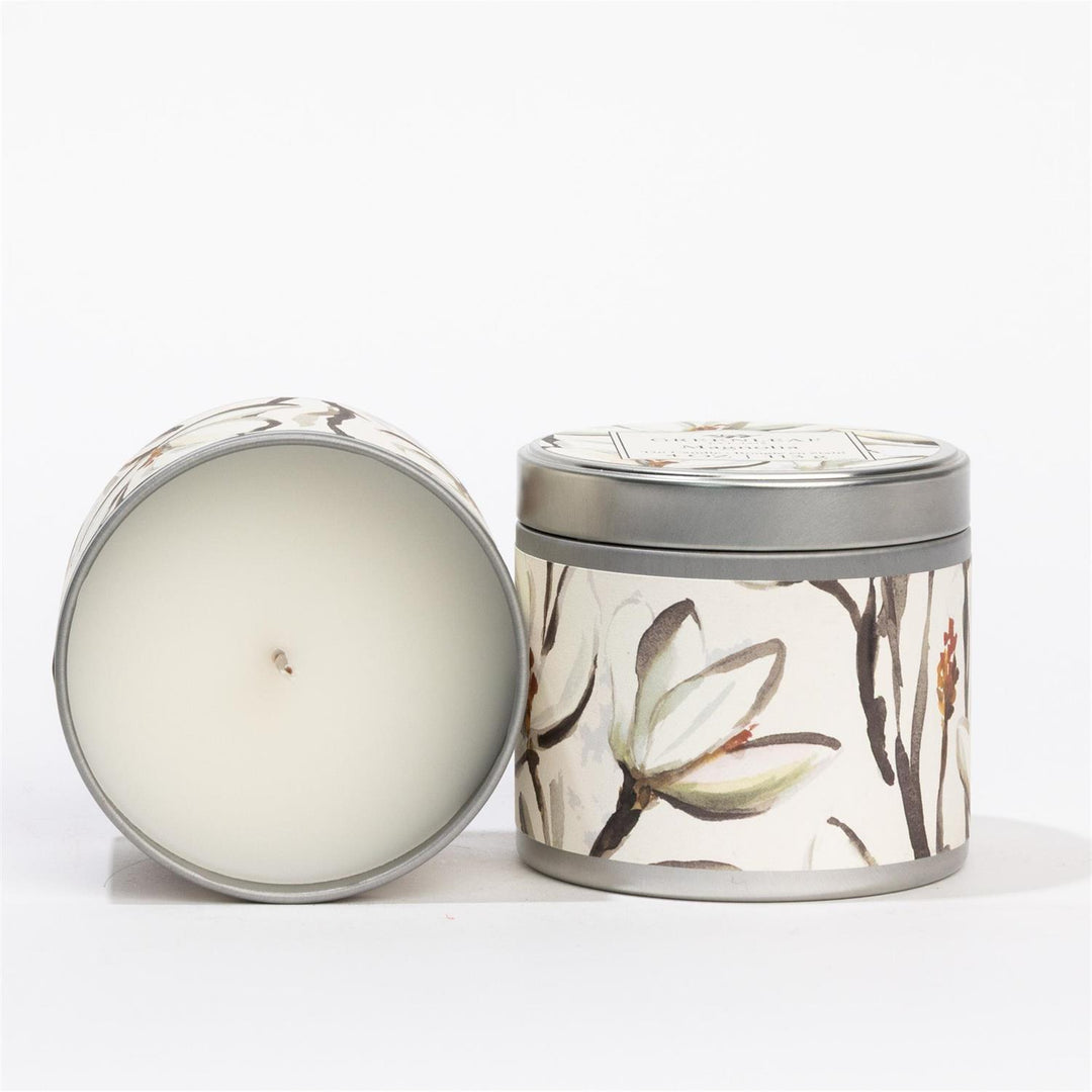 Magnolia Tin Candle with floral pattern, white wax, and lid. Delicate magnolia scent. Available in 4oz and 8oz sizes.
