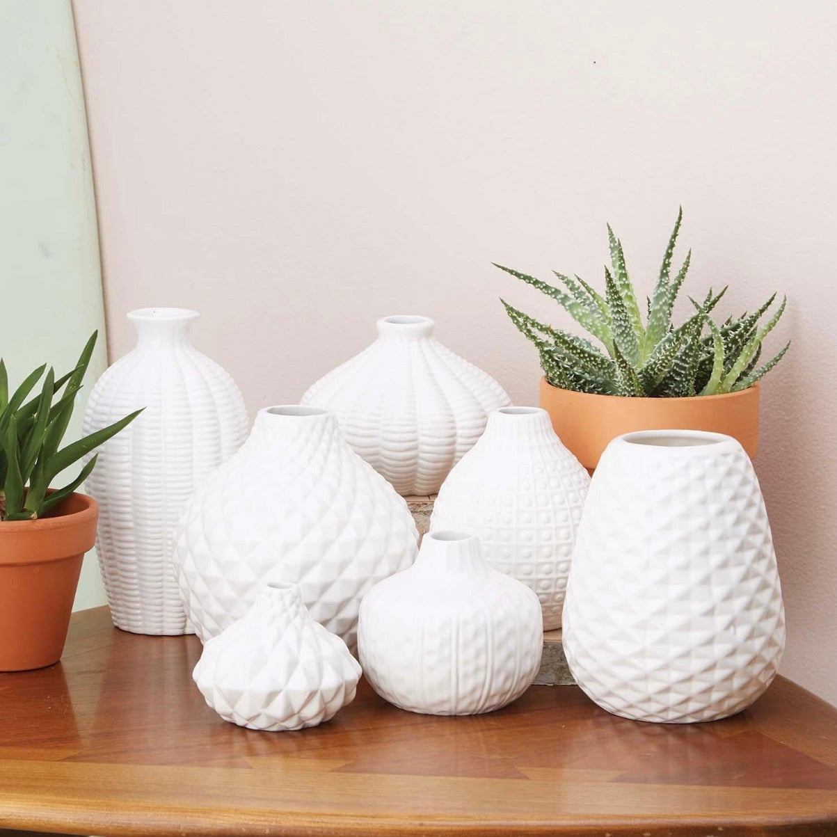 Set of seven white ceramic vases with textured finishes and various shapes, including the Artisan Carved Vase. Available in multiple sizes.