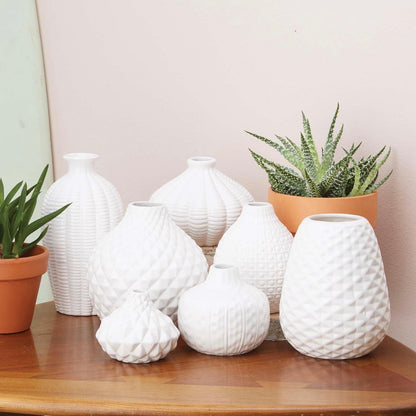 Set of seven white ceramic vases with textured finishes and various shapes, including the Artisan Carved Vase. Available in multiple sizes.