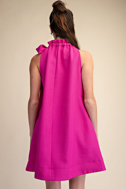 Magenta Tie-Neck Sleeveless Dress with ruffle high neckline, bow detail; available in sizes XS–XL.