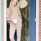 A smiling woman in a beige Champion Sweatshirt holding a mug stands in a doorway with a decorative Easter egg hanging on the door.