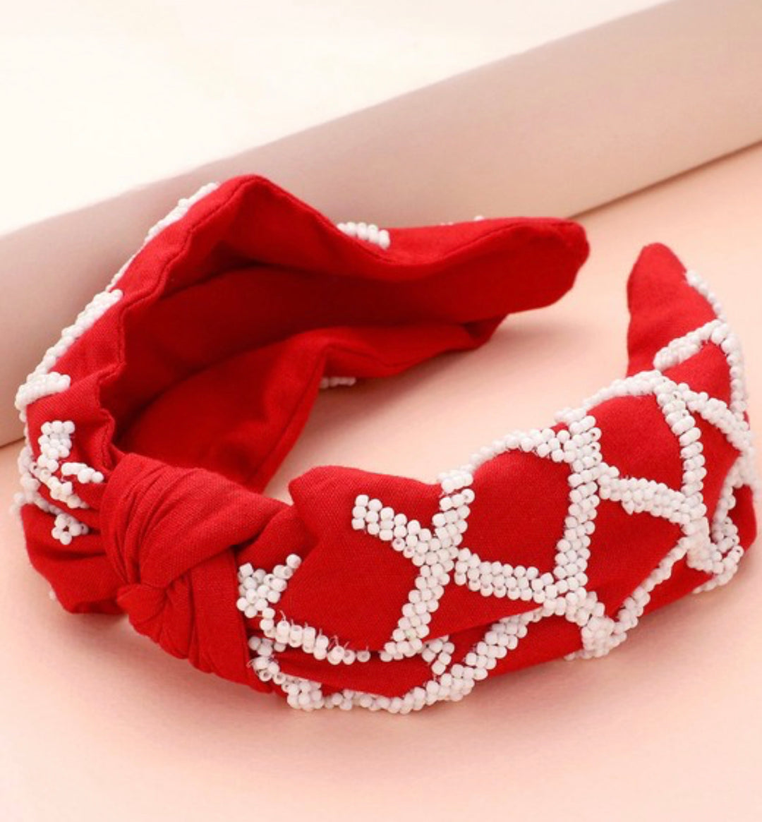 Red knot headband with white beaded crisscross design. Available in one size.