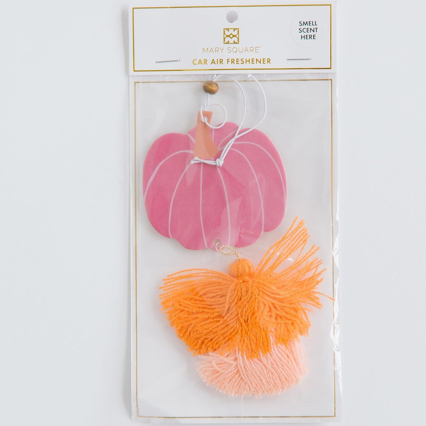 Pink pumpkin-shaped car mirror air freshener with orange and pink tassel. Scent: harvest spice and vanilla. Available Sizes: One Size. Packaging includes "Smell Scent Here" indicator.