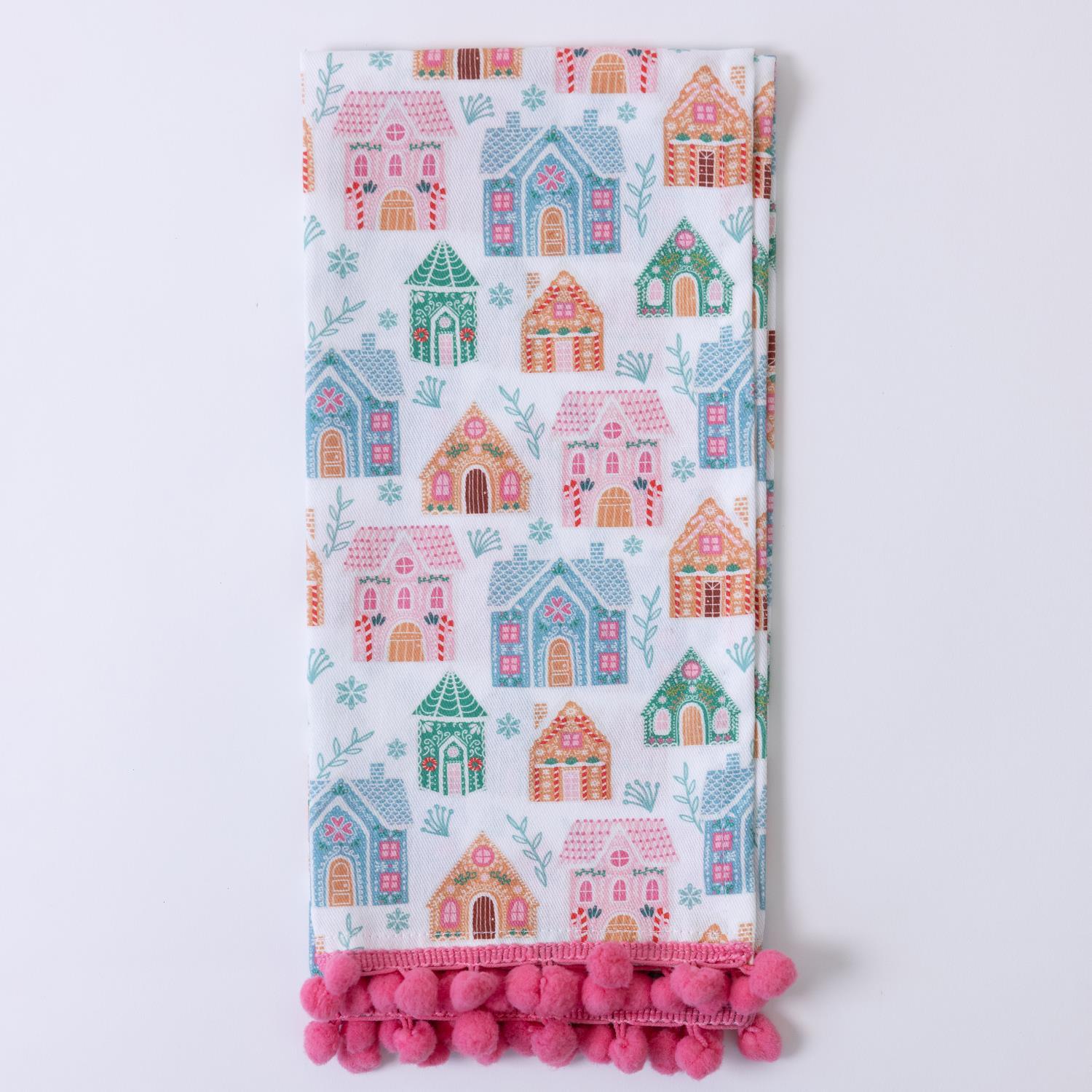 The Festive Christmas Tea Towels feature a lively design with colorful houses in pink, blue, and green, accented by leaves and branches. Edged with pink pom-poms. Available in standard size.