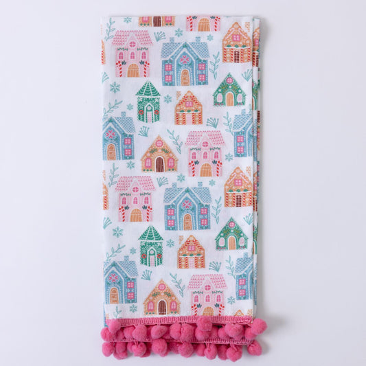 The Festive Christmas Tea Towels feature a lively design with colorful houses in pink, blue, and green, accented by leaves and branches. Edged with pink pom-poms. Available in standard size.