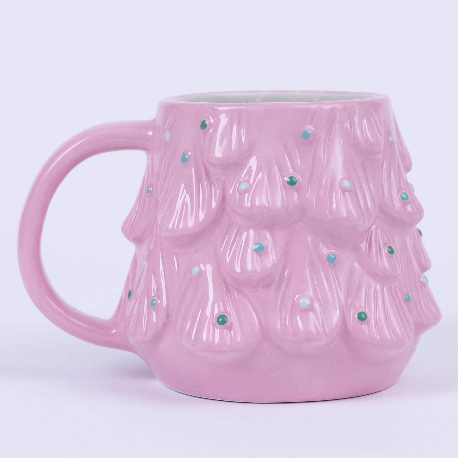 Christmas Themed Mugs: Pink ceramic mugs shaped like stylized Christmas trees with raised branch patterns, green and white dot ornaments on a light gray background, and a plain handle. Available in standard 12 oz size.