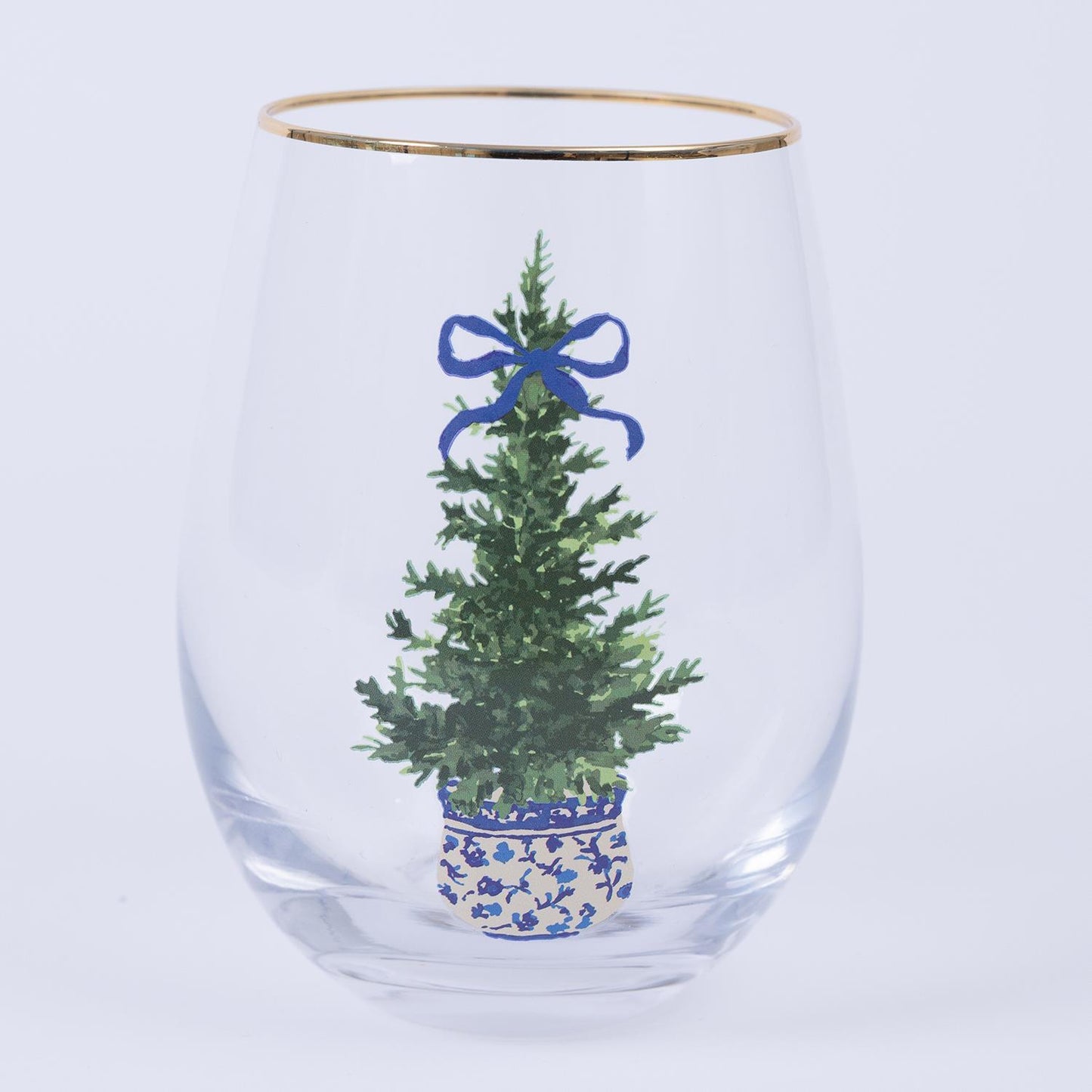 The Fancy & Festive Stemless Wine Glass features a tree design with a Christmas tree in a blue and white pot, topped with a blue ribbon and accented by gold trim. Available in 12 oz size.